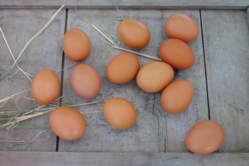 Chicken eggs in nest of straw on old wooden background.