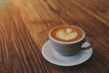 A latte coffee mug on the brown wood table with morning light