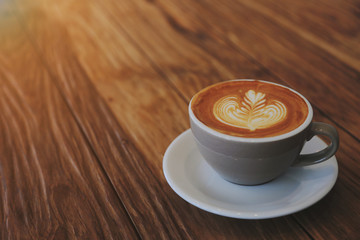 A latte coffee mug on the brown wood table with morning light