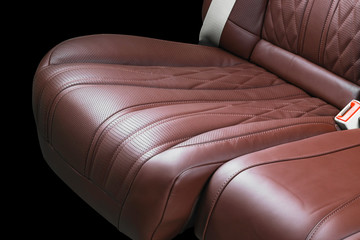 Brown leather interior of the luxury modern car. Perforated Leather comfortable red seats with stitching isolated on black background. Modern car interior details. Car detailing. Car inside