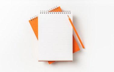 Top view of orange spiral notebook, page, pencil