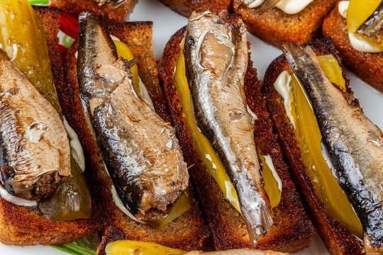 Background, sprats with pickles lie on toasted bread. Close-up.