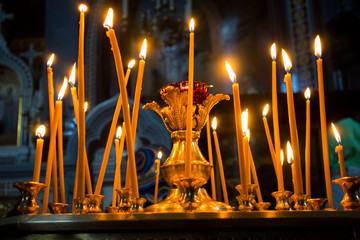 Many burning wax candles in the orthodox church or temple - obrazy, fototapety, plakaty