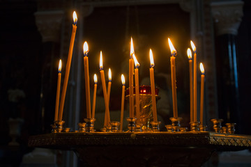 Many burning wax candles in the orthodox church or temple
