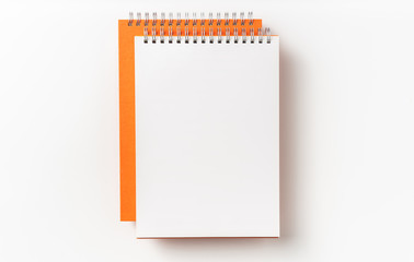 Top view of orange spiral notebook, page, pencil