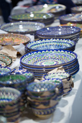 Bright oriental colored plates. Authentic dishes hand-painted in national style. Beautiful bowls and plates in the oriental bazaar. Bright background illustrating the national oriental style.