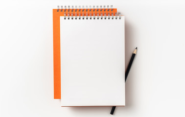 Top view of orange spiral notebook, page, pencil
