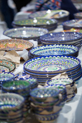 Bright oriental colored plates. Authentic dishes hand-painted in national style. Beautiful bowls and plates in the oriental bazaar. Bright background illustrating the national oriental style.