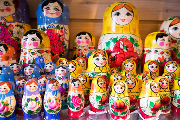 Fototapeta na wymiar Dolls, Matryoshka Doll, in Gift Shop Shelf. Colorful Set of Various Wooden Stacking Women Figure Dolls in Traditional Old Russian Clothes.