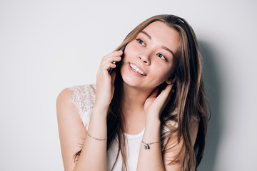 Young woman talking on phone on a white background. A Fun beautiful smiling girl