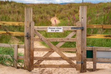 Sign: Please close the gate, seen on a closed gate in Ross Sands near Seahouses in Northumberland,...