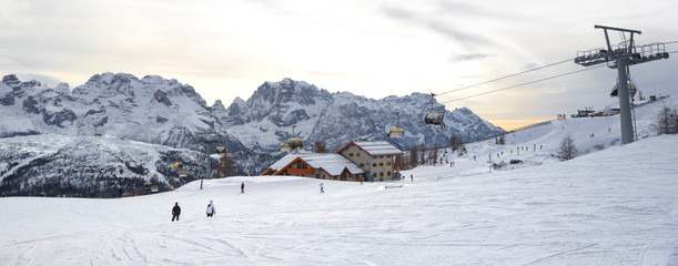 ski slopes with skiers at sunset. Trentino, Italy
