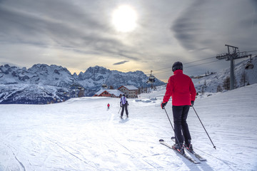 Fototapeta na wymiar ski slopes with skiers at sunset. Trentino, Italy