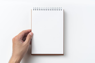 Top view of brown spiral notebook with hand