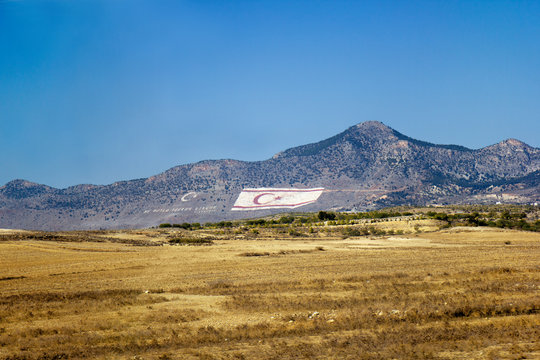 The huge flag of Flag of the Turkish Republic of Northern Cyprus is painted on the Kyrenia Mountains, facing the Southern Cyprus. 