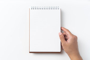 Top view of brown spiral notebook with hand