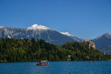 Iconic landscape view of beautiful  St. Marys Church of Assumption on small island,lake Bled in Slovenia .Bled Castle on background. Summer scene travel Slovenia concept. Tourist popular attraction