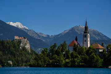 Fototapeta na wymiar Iconic landscape view of beautiful St. Marys Church of Assumption on small island,lake Bled in Slovenia .Bled Castle on background. Summer scene travel Slovenia concept. Tourist popular attraction