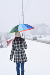 Back view on women walking in the city on blizzard. Woman walks through snow on sidewalk
