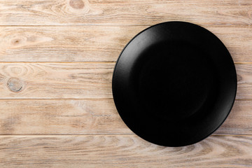 Directy above Empty black matte dish for dinner on orange wooden background with copy space