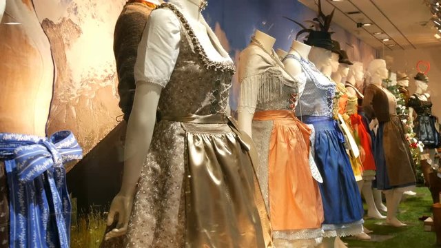 Beautiful various women's national Bavarian costumes dirndl and men's lederhosen on shop window