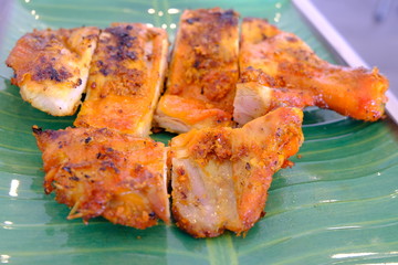Grilled chicken placed on a green plate with marinated with Thai style sauce.