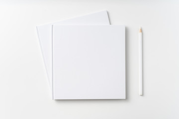 Top view of 2 white hardcover notebook, pencil
