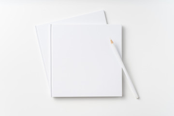 Top view of 2 white hardcover notebook, pencil