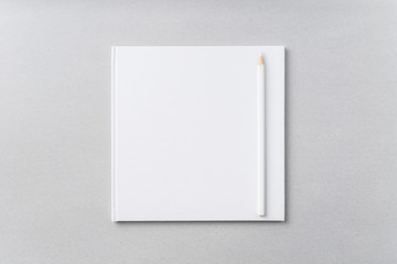 Top view of white hardcover notebook, pencil