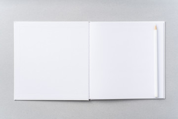 Top view of white hardcover notebook, pencil