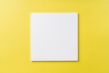 Top view of white hardcover notebook on yellow