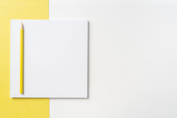 Top view of white hardcover notebook, pencil