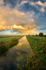 Evening autumn shower over the dutch countryside near Gouda, illuminated by the setting sun.  One of the many canals in the western part of the Netherlands during the Golden Hour.