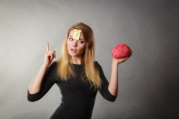 Woman thinking and holding fake brain