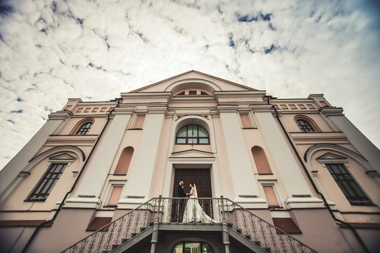 husband and wife posing for a photo near an old architectural building