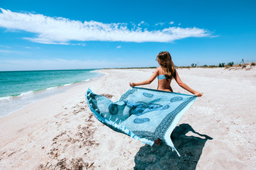 Girl holding pareo on the beach - obrazy, fototapety, plakaty
