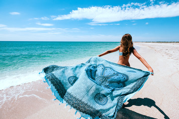 Girl holding pareo on the beach - obrazy, fototapety, plakaty