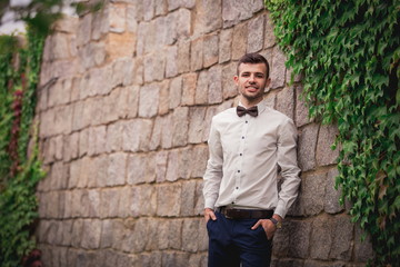 stylish bride's husband, with dark hair and unshaven face, in a shirt, preparing for a wedding