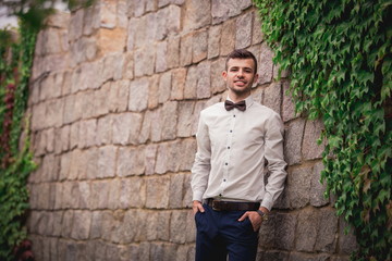 stylish bride's husband, with dark hair and unshaven face, in a shirt, preparing for a wedding