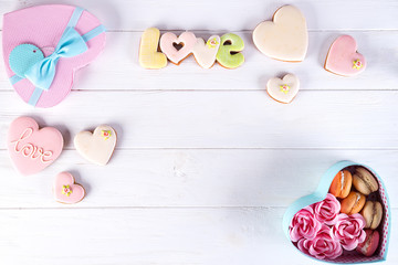 Hearts cookies and macaroons in box. Festive round blue box with cookies and Rose on white wooden background, flat lay with copy space