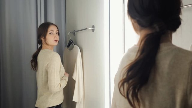 Beautiful woman measures the clothes in a fitting room