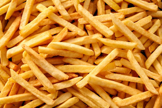 Overhead view of golden deep fried French fries food in full frame closeup.