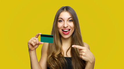 Close up portrait of cheerful young girl with long hair showing and pointing finger credit card...