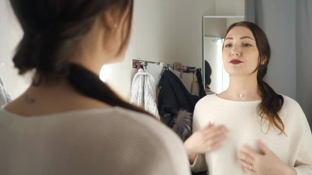 Fashionable girl looking in the mirror in fitting room