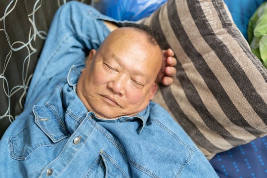 I'm completely exhausted : Old Asian Man peacefully sleeping at home.