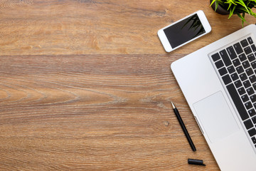 Wood office desk table with smartphone, laptop computer and pen. Top view with copy space, flat lay.