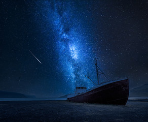 Milky way over a shipwreck on the shore in Iceland