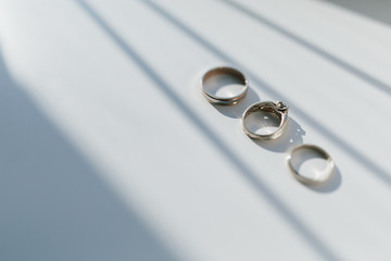 Wedding and engagement rings lie on a white background with a shadow