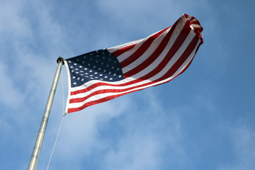 American flag on a pole flying against bright blue skies