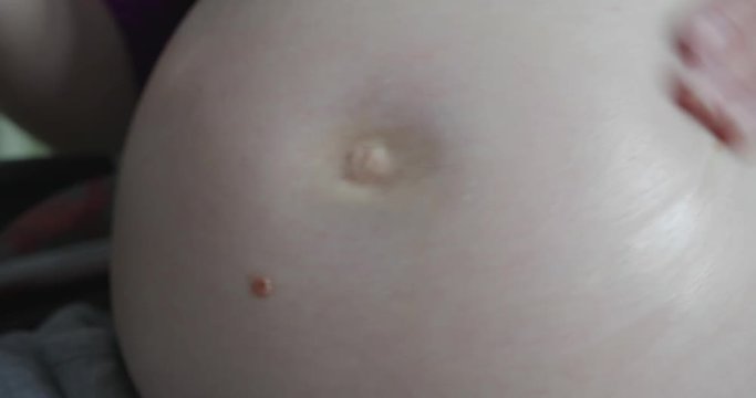 pregnant woman massages belly with oil
